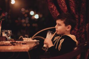 A young boy sipping a milkshake at a restaurant table during a cozy evening.